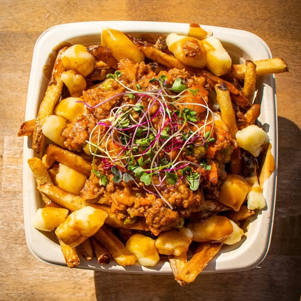 A close-up of The Flying V's poutine with fries, cheese curds, gravy, and microgreens.