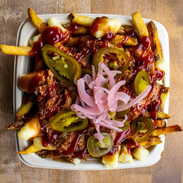 The Flying V's poutine with fries, cheese curds, pulled pork, BBQ sauce, jalapeños, and pickled onions.