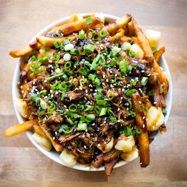 The Flying V's comfort-food poutine with fries, cheese curds, gravy, pulled pork, green onions, and sesame seeds.